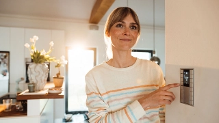 Frau in Ihrem Eigenheim stellt in ihrem energieeffizienten Zuhause die Heizung ein.